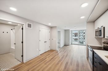 a renovated living room and kitchen with white walls and wood floors